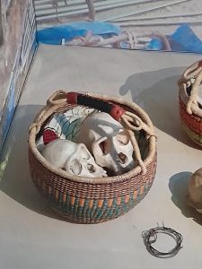 Wicker basket with colourful weaving throughout. The basket is lined with colourful fabric and is being used to display primate skulls.