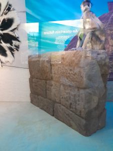 Scenic prop resembling a stone wall. It is installed in a museum display with a taxidermy monkey specimen placed on top.